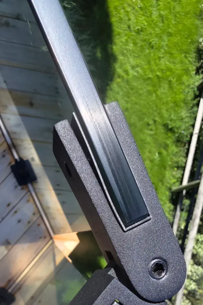 Close-up of a glass railing spigot clamp securing tempered glass panel